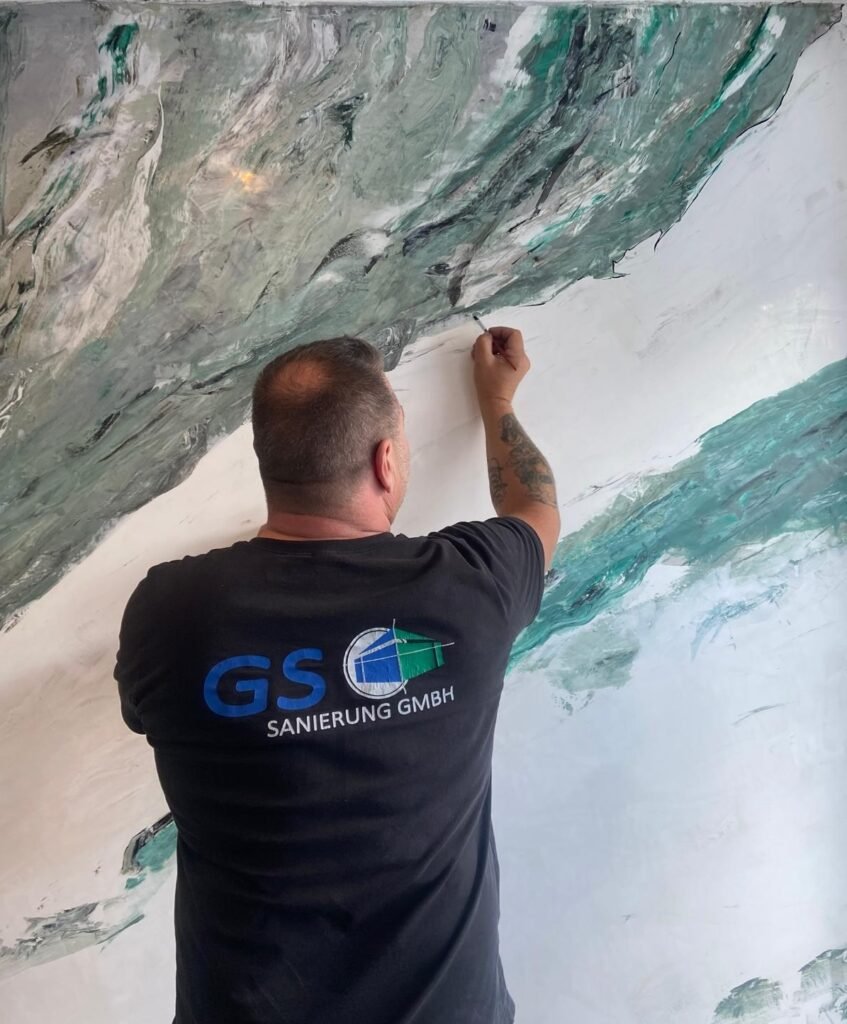 Mann malt an einer Wand.