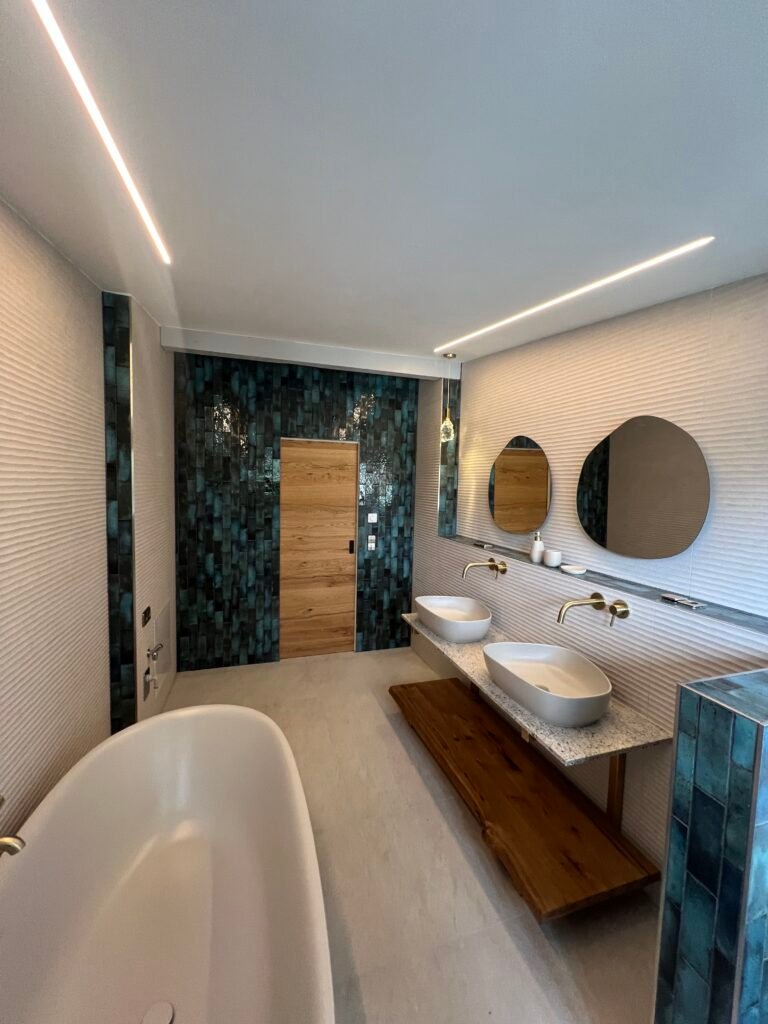Renoviertes Bad mit freistehender Wanne, Doppelwaschtisch und türkis-schwarzer Fliesenwand, Badsanierung